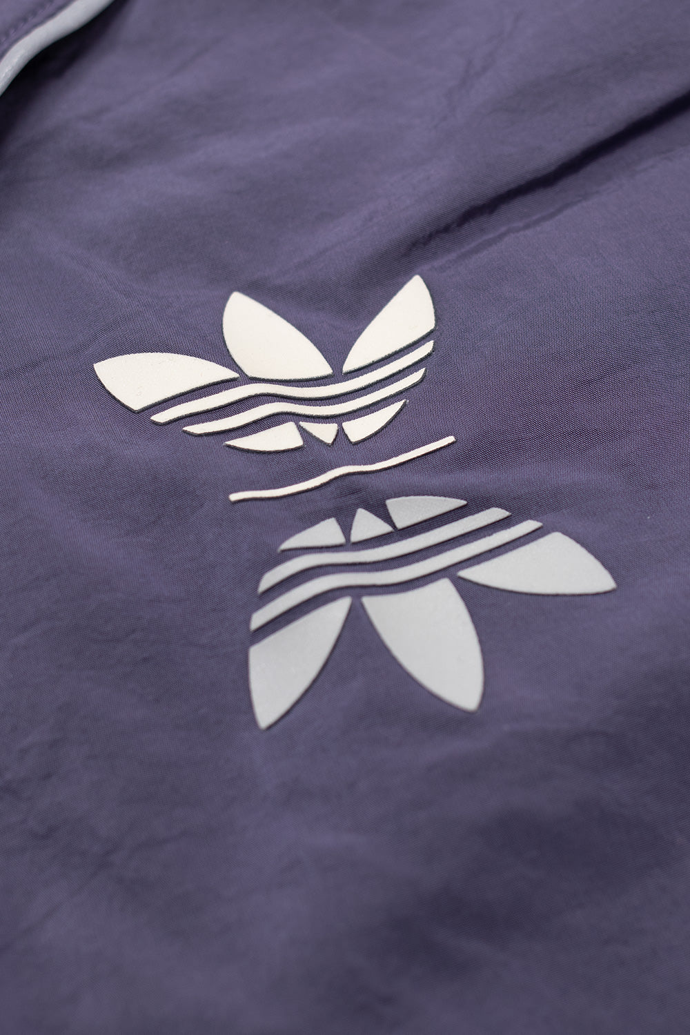 Detail shot of printed Adidas Trefoil and Metalwood Studio chest logos on purple technical crew sweatshirt with lightweight performance fabric.