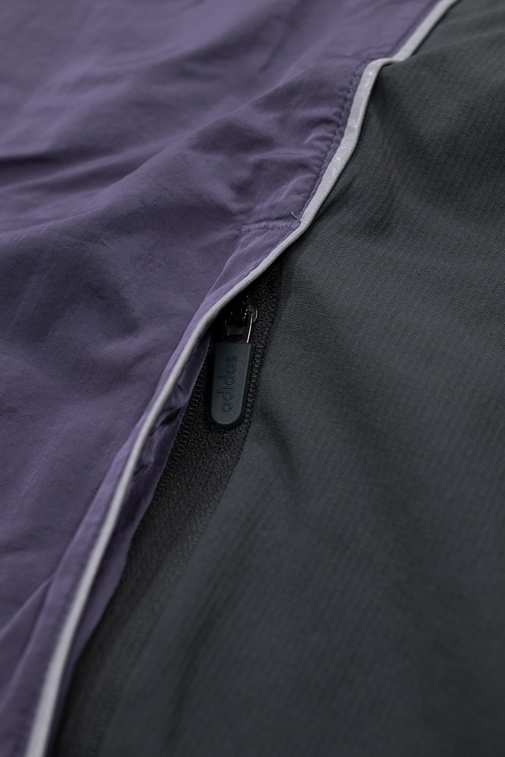 Macro view of reflective seam piping and panel construction on Adidas x Metalwood oversized sweatshirt highlighting Y2K techwear inspiration.