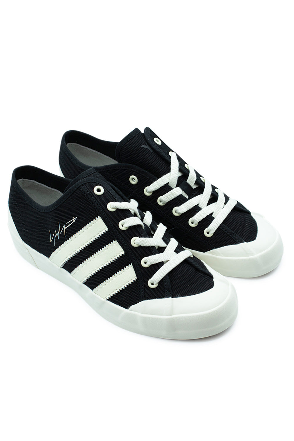 Three-quarter studio perspective shot of both Adidas Y-3 Nisi Lo Black / Off White sneakers, detailing the unique avant-garde low-cut silhouette, contrasting off-white 3-Stripes on the lateral side, off-white laces, and rubber toe cap.