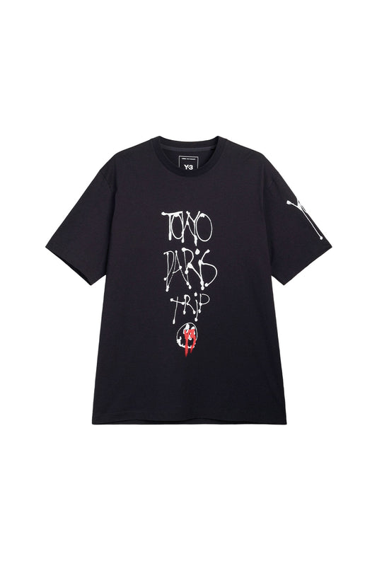 Front view of the black Adidas Y-3 X Chito City Graphic Short Sleeve Tee, crafted from premium cotton jersey with vertical white dripping tag lettering reading TOKYO PARIS TRIP, a small circular face with red spray paint overlay, and a white graffiti tag printed on the left sleeve.