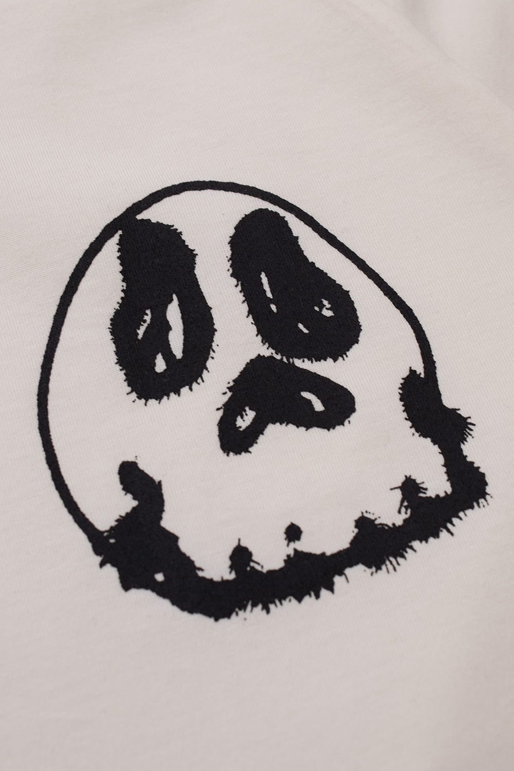 Macro shot highlighting the black screen-printed skull artwork with sprayed stencil texture on the front panel of the Adidas Y-3 X Chito collaboration tee.
