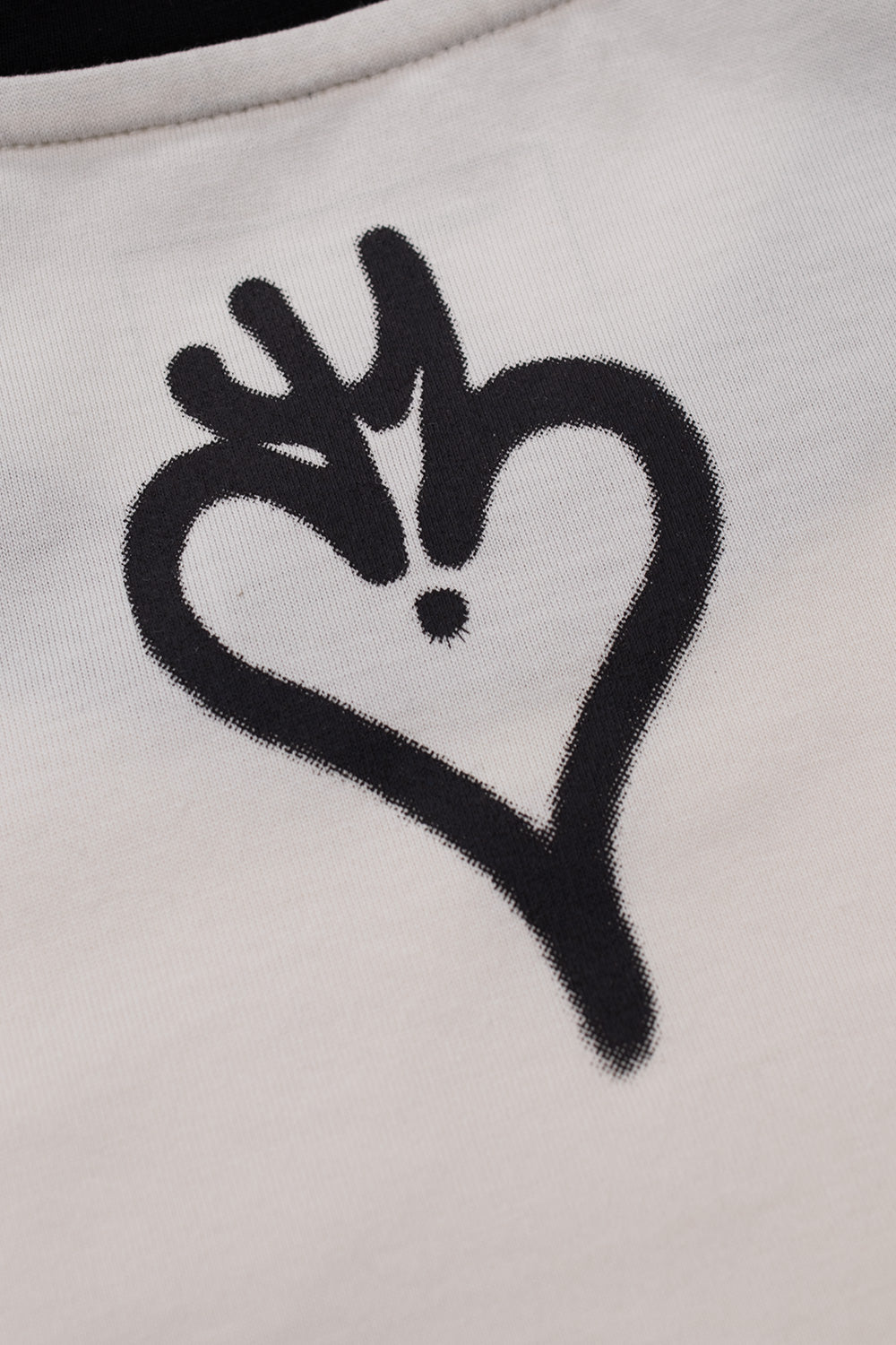 Extreme close-up view of the black airbrushed heart motif print located on the upper back neck below the collar ribbing on the Adidas Y-3 X Chito Graphic Cali T-shirt.