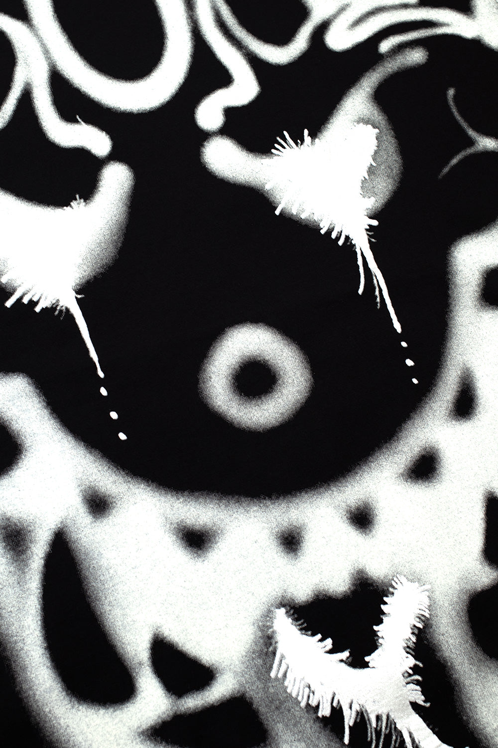 Macro detail shot of the white airbrushed artwork printed on the black cotton chest of the Adidas Y-3 X Chito long sleeve tee, highlighting fine spray can misting, dripping dots, and feathered brush texture.