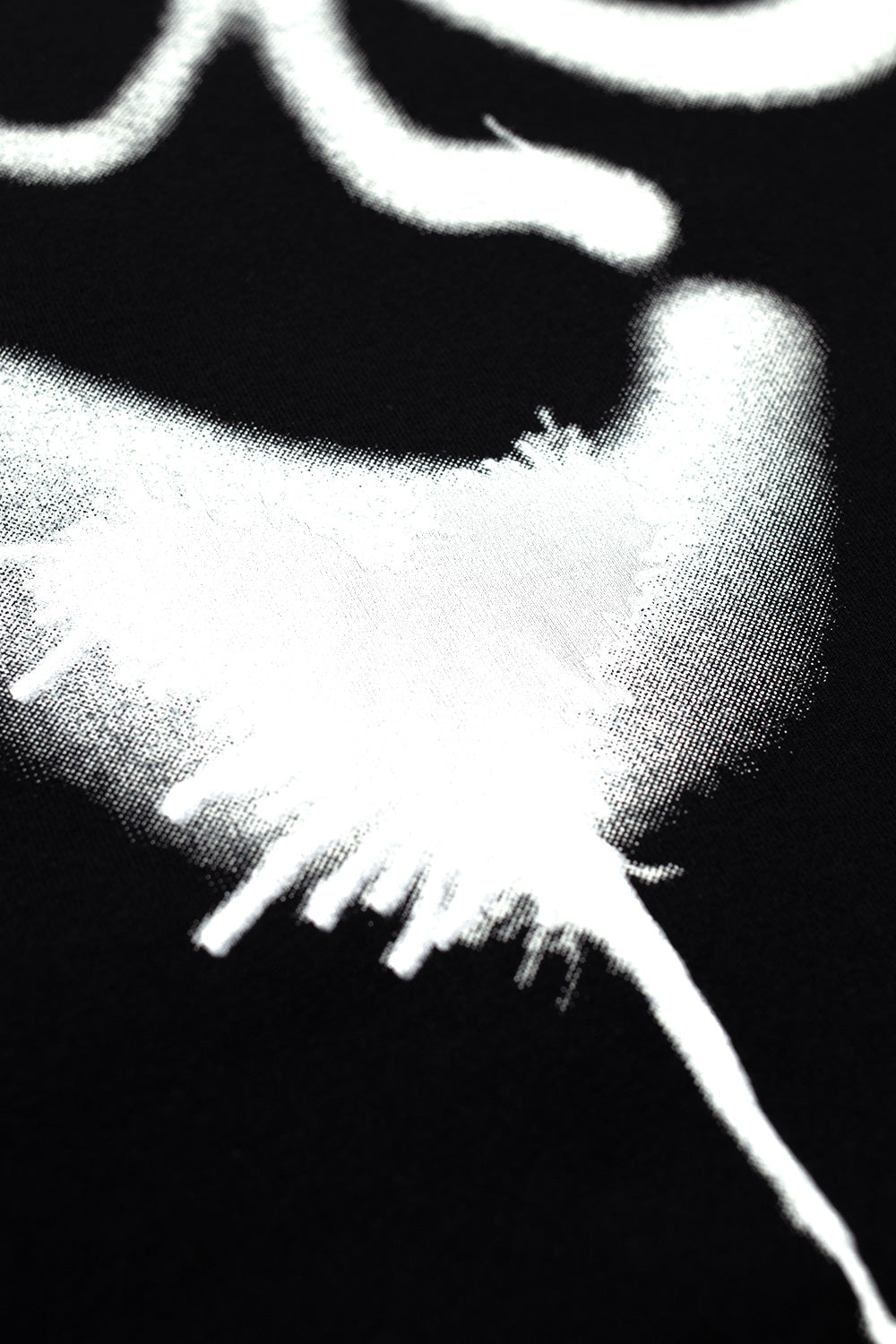 Close-up view of the high-contrast white stencil spray graphic printed on the black cotton jersey material of the Adidas Y-3 X Chito collaboration long sleeve shirt.