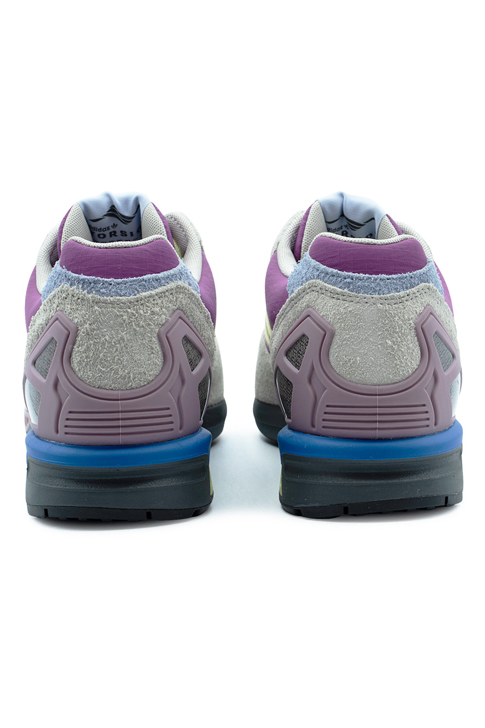 Rear perspective shot of the heels of the Adidas ZX 8000 sneakers, showing the semi-translucent mauve TPU external heel counter cages, grey hairy suede collar trim, royal blue heel midsole block, padded grey textile lining, and woven internal tongue labels reading "adidas TORSION".