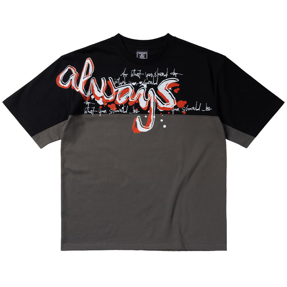 Front flat lay view of the Always Waza Panelled T-Shirt in grey and black, featuring a heavy cotton cut-and-sew two-tone construction with a black upper chest and sleeves, dark grey lower body, wide loose fit, and a prominent graffiti-style chest print displaying white bubble script reading "always" outlined with orange and red spray-paint splatters and scribbled white typography across the horizontal center seam.