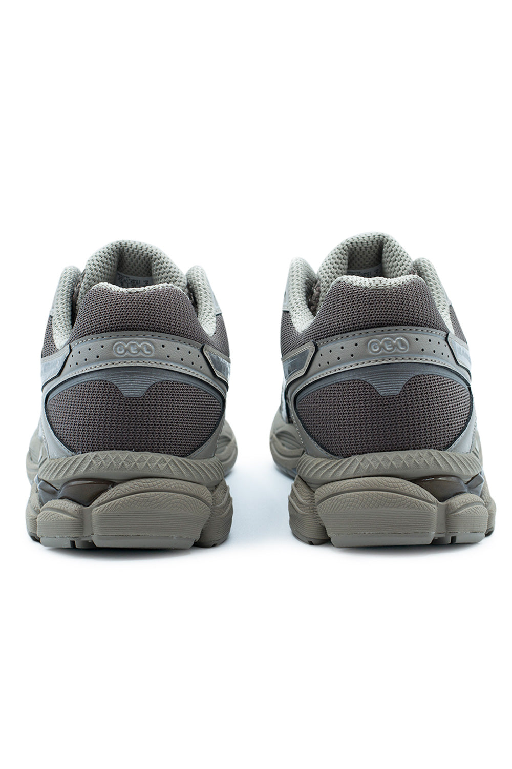Rear perspective shot of the heels of the Asics Gel-Cumulus 16 shoes, displaying the plush grey collar padding, dark cocoa mesh heel counter panels, structured silver synthetic support cages with embossed GEL branding, and segmented dark grey rubber outsole wrapped securely around the base.