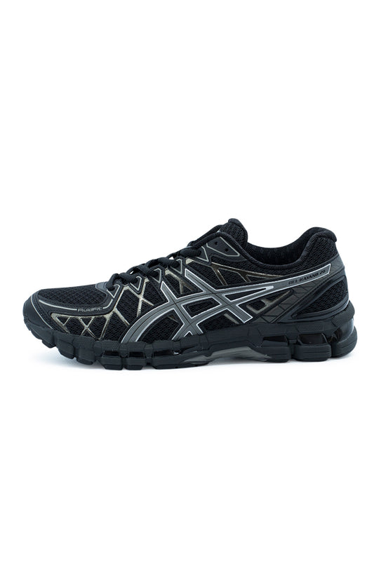 Lateral profile view of the Asics Gel-Kayano 20 sneaker in Black and Clay Grey, featuring an open black honeycomb mesh upper reinforced by the geometric FLUIDFIT synthetic cage, grey Asics tiger stripes with reflective outlines, a black sculpted midsole with visible rearfoot GEL cushioning units, and "GEL-KAYANO 20" branding on the lateral heel collar.