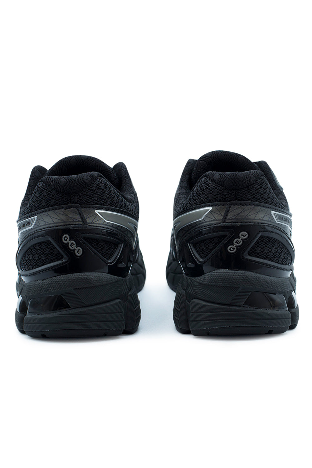 Rear perspective shot of the heels of the Asics Gel-Kayano 20 sneakers, showcasing the padded black textured mesh collars, gloss black TPU external heel counter stability cages with embossed oval GEL lettering, grey geometric reflective heel accents, and the segmented black rubber outsole base.
