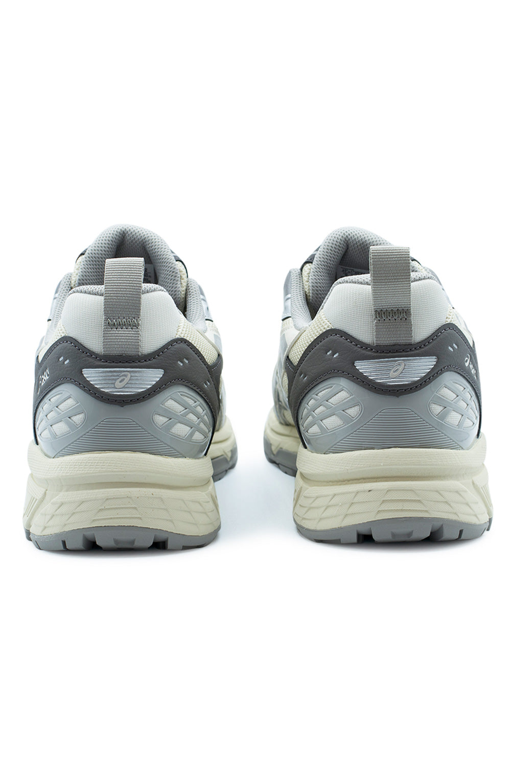 Rear perspective view of the heels on the Asics Gel-Nunobiki in Cream and Cement Grey, highlighting the grey textile collar lining, webbing heel pull loop, grey synthetic heel counter overlay with reflective insert, and segmented cream and grey rubber outsole.