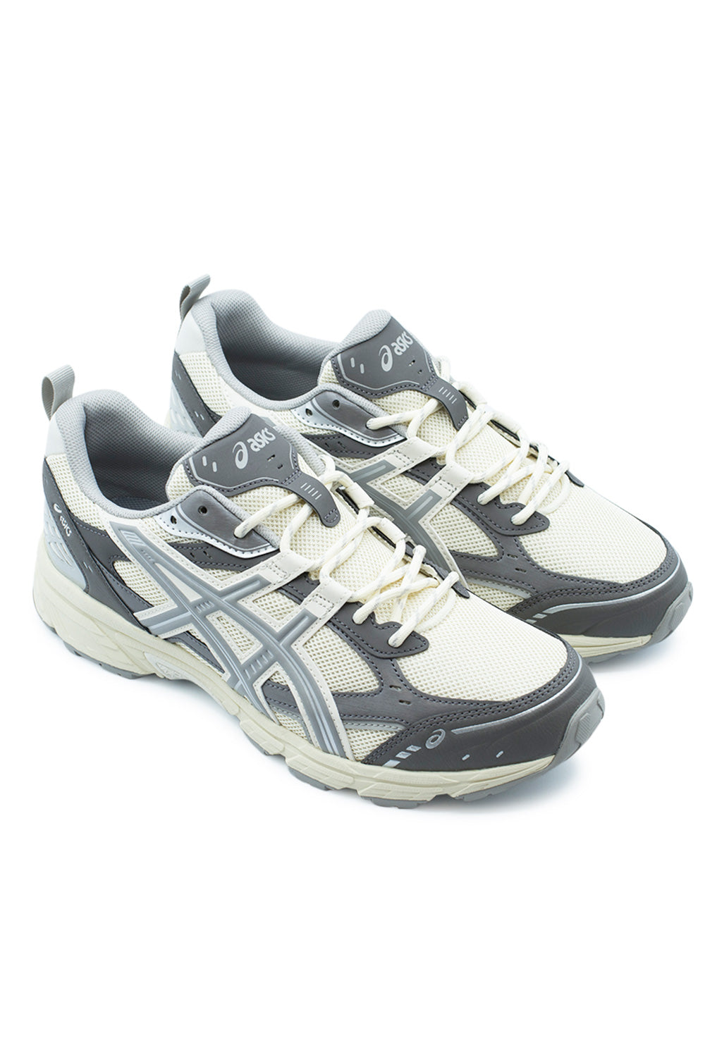 Elevated three-quarter studio perspective of the Asics Gel-Nunobiki in Cream and Cement Grey, illustrating the functional early-2000s trail silhouette inspired by the archival Gel-Kahana 3 and Gel-Target with dynamic layered panelling.