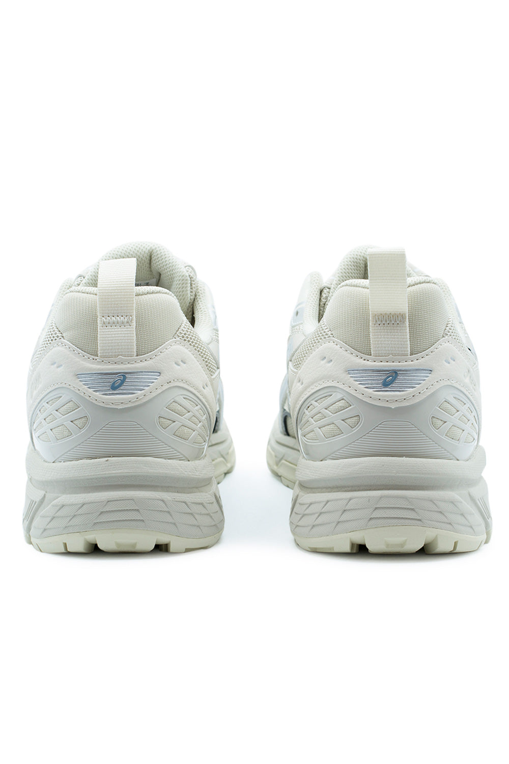 Rear perspective shot of the heels on the Asics Gel-Nunobiki sneakers, highlighting the padded textile collar, vertical off-white grosgrain heel pull tabs, semi-translucent slate blue Asics spiral logos, geometric TPU heel counter reinforcements, and grooved off-white foam midsole.