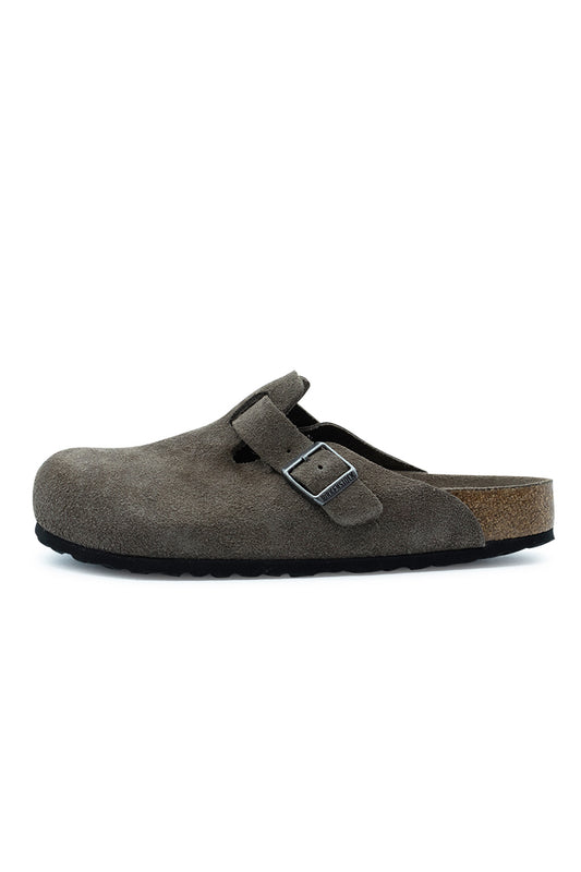 Lateral side profile view of the Birkenstock Boston BS Clog in Concrete Grey suede, displaying the smooth closed-toe upper, adjustable instep strap with a gunmetal metal pin buckle, natural cork-latex midsole layer, and black EVA outsole.