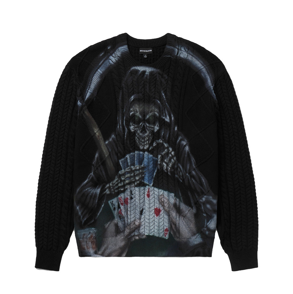 Front flat lay studio view of the Born X Raised Two Pair Cable Knit Sweater in black, showcasing a heavyweight crewneck knitwear silhouette with classic braided cable-knit patterns, ribbed collar, cuffs, and hem, centered by a large photorealistic airbrush-style print of the Grim Reaper holding playing cards and a scythe.