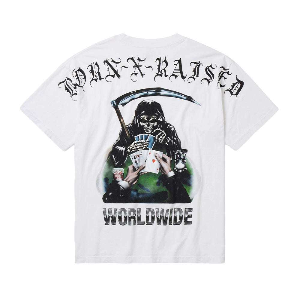 Back flat lay studio view of the Born X Raised Two Pair T-Shirt in white, featuring a boxy heavyweight cotton skate tee cut, centered by an elaborate full-color airbrush-style graphic depicting the hooded Grim Reaper holding a scythe across a poker table with playing cards, a whiskey glass, and an hourglass, framed by arched black Old English Gothic "BORN-X-RAISED" lettering across the upper shoulders and bold chrome-shaded "WORLDWIDE" typography along the bottom.