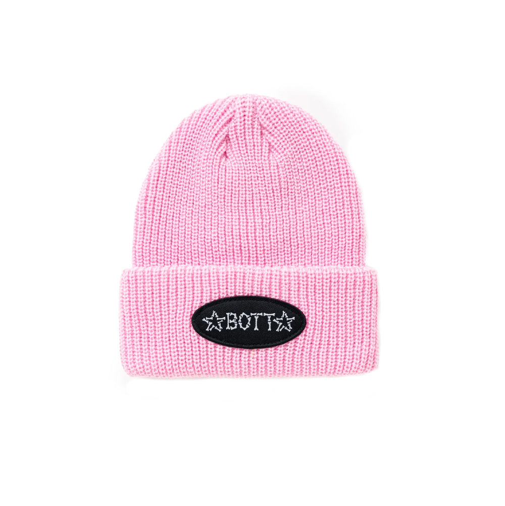 Front flat lay studio view of the BoTT Bones Cuff Beanie in pastel baby pink, showcasing a chunky vertical ribbed-knit acrylic fisherman beanie with a wide turnover cuff, centered with an oval black woven twill patch featuring white embroidered "BoTT" lettering and flanking stars constructed from illustrated skeletal bones.