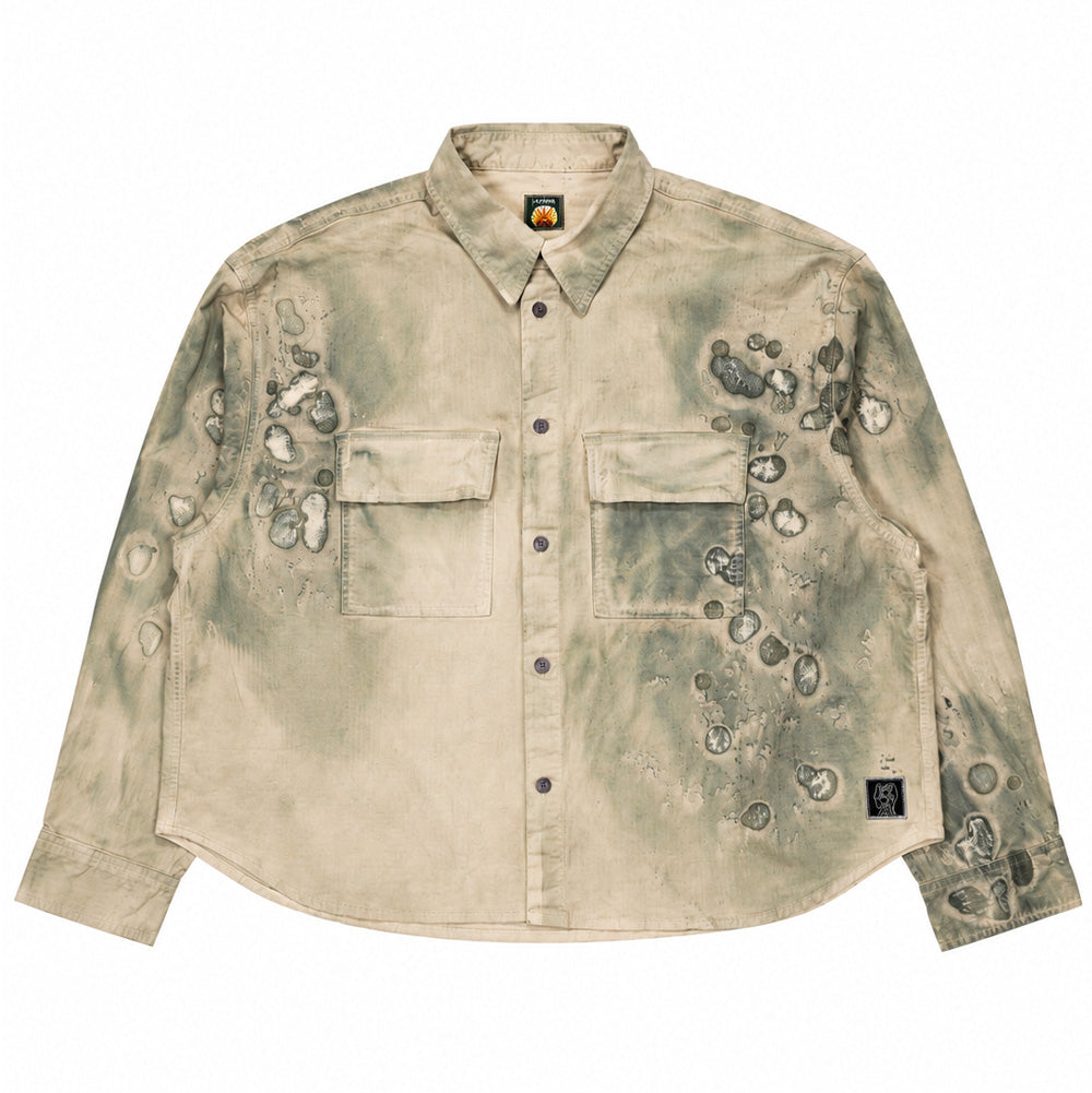 Front flat lay studio view of the Brain Dead Cotton Ripstop Cropped Shirt Jacket in the Algae colorway, showcasing a boxy, wide-cut overshirt silhouette made from durable textured cotton ripstop, featuring a pointed turn-down collar, button-down front with iridescent mother-of-pearl buttons, two oversized flap chest pockets, a subtle curved hemline, and an experimental all-over overprinted pattern resembling microscopic algae cell cultures and organic bleach spatters.