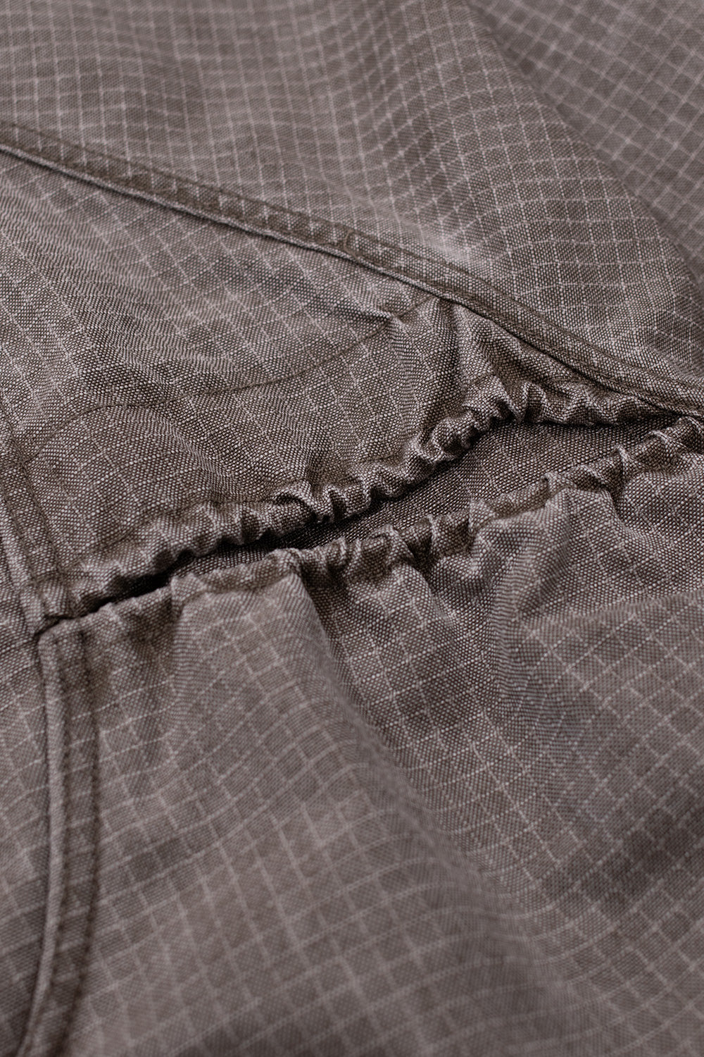 Detailed view of Brain Dead Washed Ripstop Equipment Half Zip Brown outerwear construction featuring reinforced seams, ripstop grid fabric and gathered elastic panel