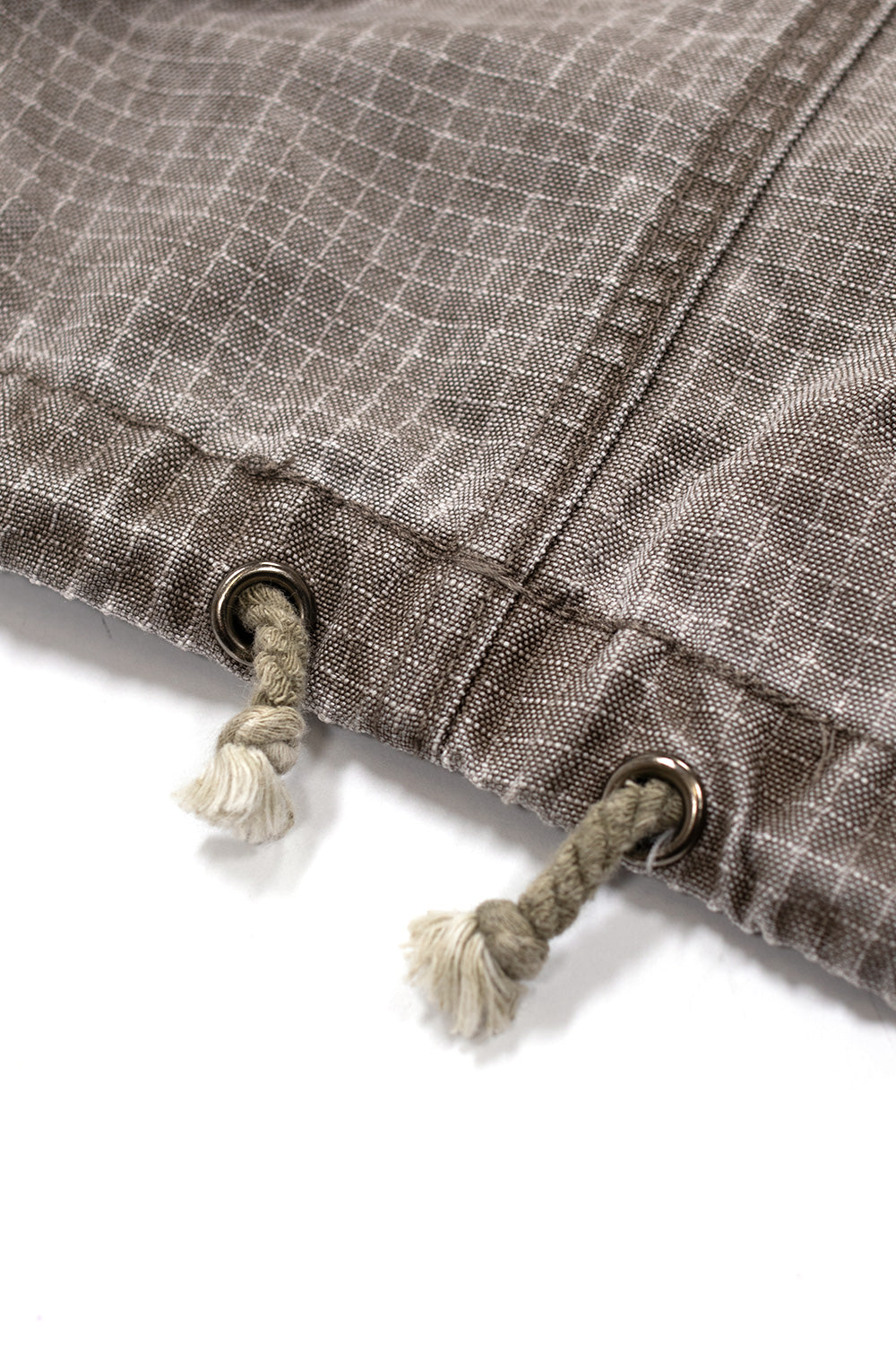 Adjustable hem drawstring detail on Brain Dead Washed Ripstop Equipment Half Zip Brown jacket showing metal eyelets and rope cord on technical ripstop streetwear pullover