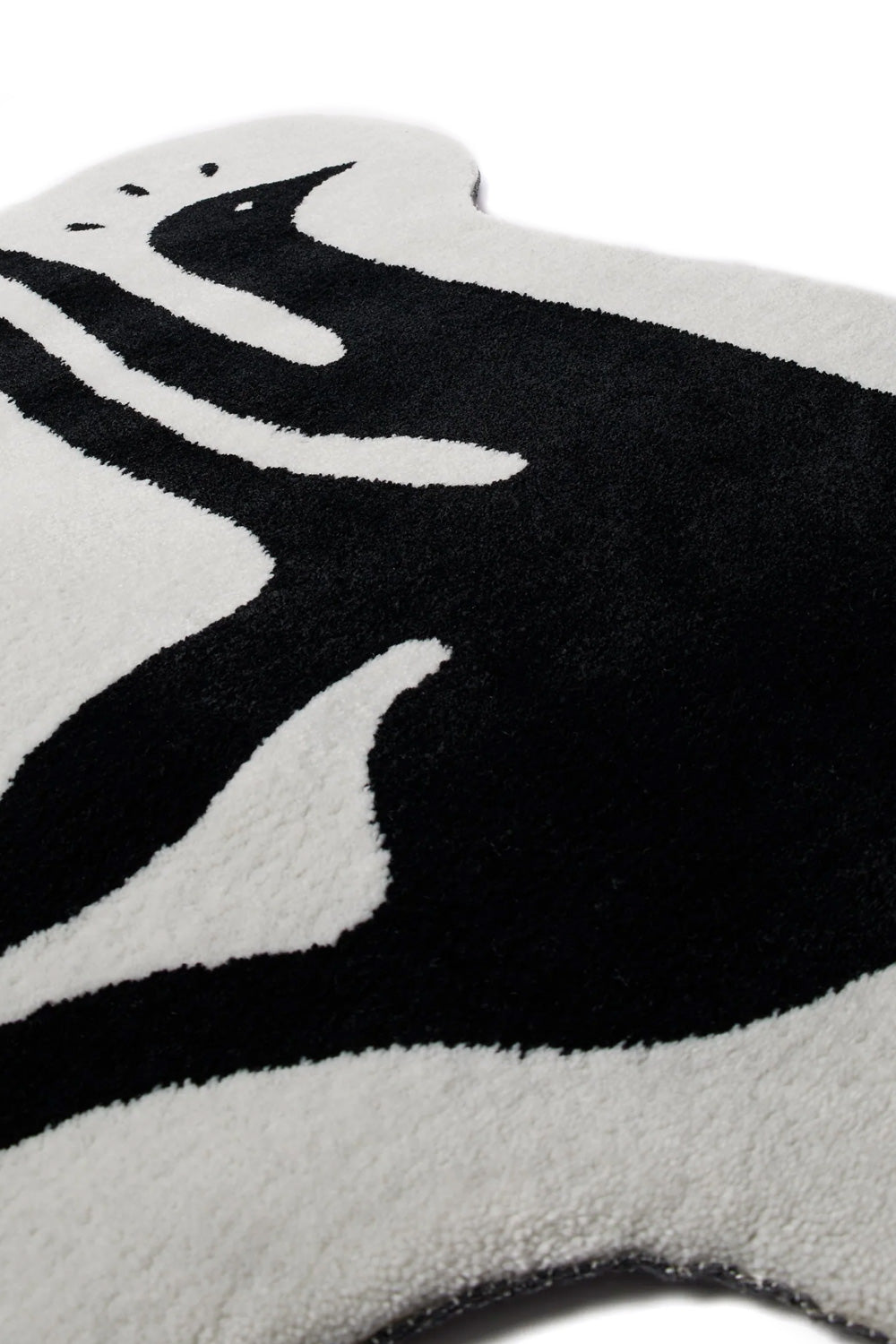 Close-up surface perspective shot of the By Parra High Heel Gloves Tufted Rug, highlighting the dense cut-pile texture of the white and deep black wool-feel yarns and the crisp silhouette contour of the surreal creature's head and limbs.