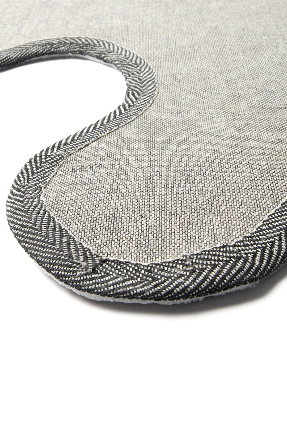 Macro detail shot of the bottom corner of the By Parra rug, showing the durable textured anti-slip backing weave and the thick herringbone-stitched edge tape securing the perimeter of the die-cut rug.