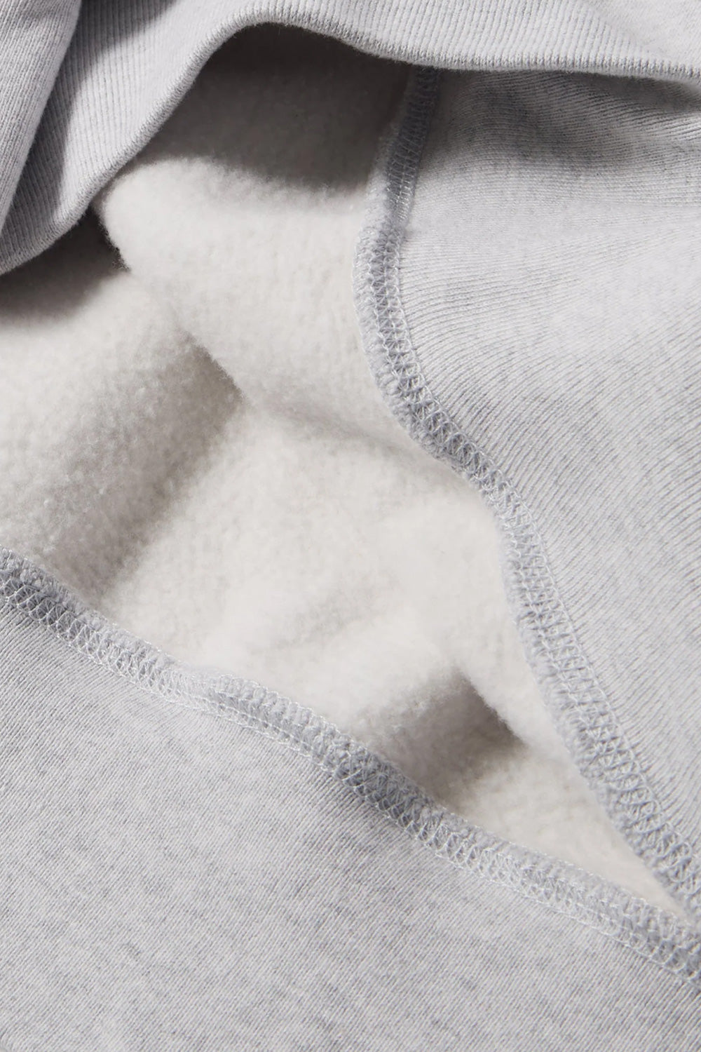 Macro shot showing the soft brushed fleece interior lining and heavy 420 grams cotton-polyester blend fabric texture of the heather grey By Parra crewneck pullover.