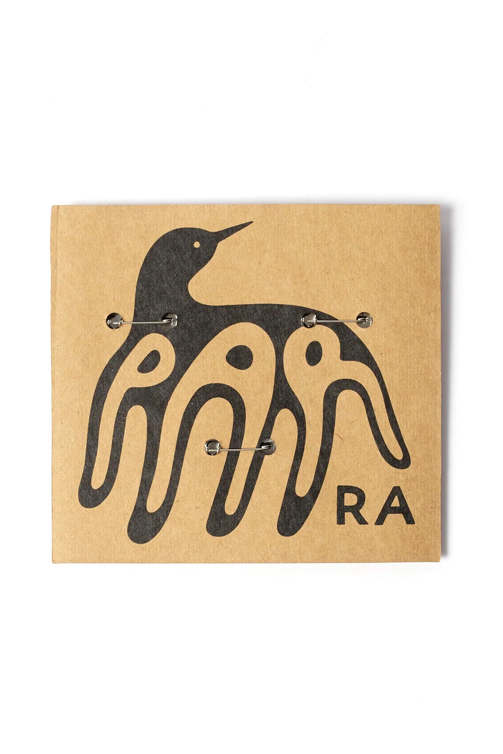 Rear perspective view of the By Parra Some Butonis Pin-Back Set packaging, showing the reverse side of the brown kraft backing card secured with three silver metal safety pin clasps and printed with a large black graphic illustration of a bird hybrid creature integrated into abstract "PARRA" typography.