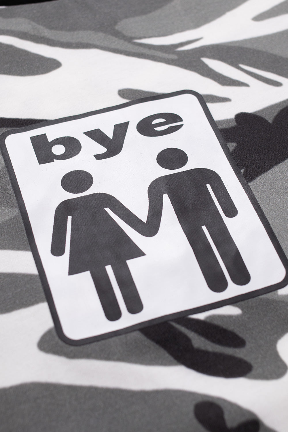 Close-up of Bye Jeremy Snow Camo Longsleeve chest print showing ‘bye’ couple icon on grey camo fabric, highlighting high-quality cotton material and streetwear-driven skate aesthetics.