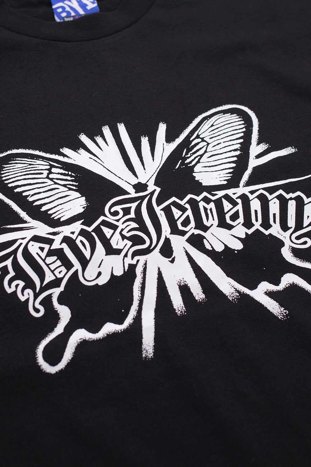 Close-up of Bye Jeremy Loco T-Shirt Black featuring detailed white butterfly print and gothic logo lettering on premium heavyweight cotton skatewear.