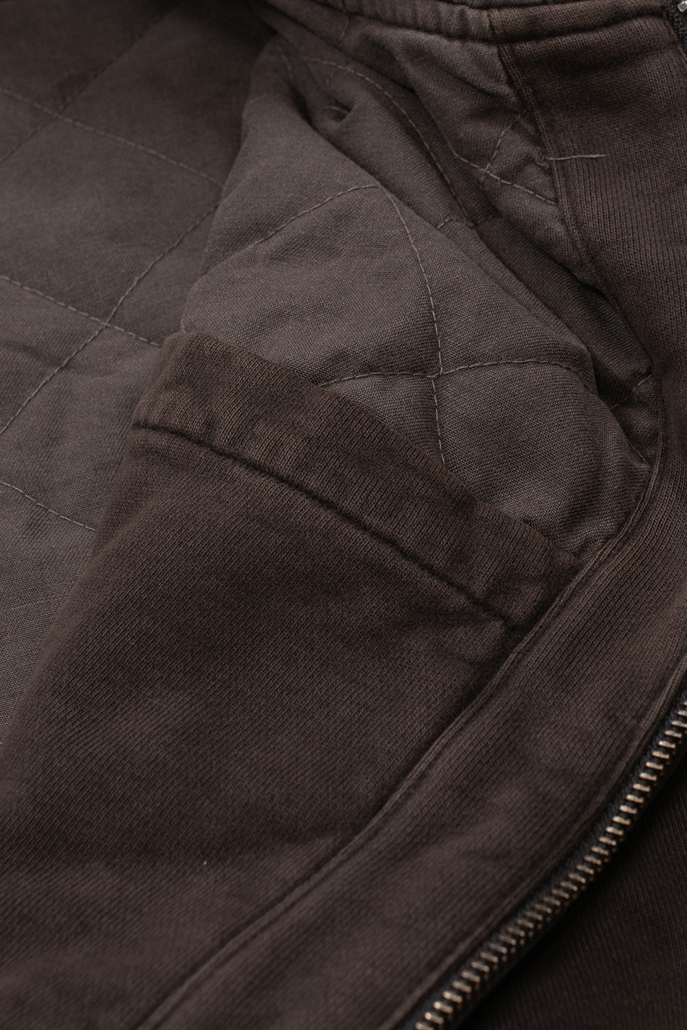 Macro detail shot of the interior construction of the Carhartt WIP Hooded Vista Jacket, revealing the insulating diamond-quilted padded lining, neat inner pocket facing, and sturdy metal zipper track.