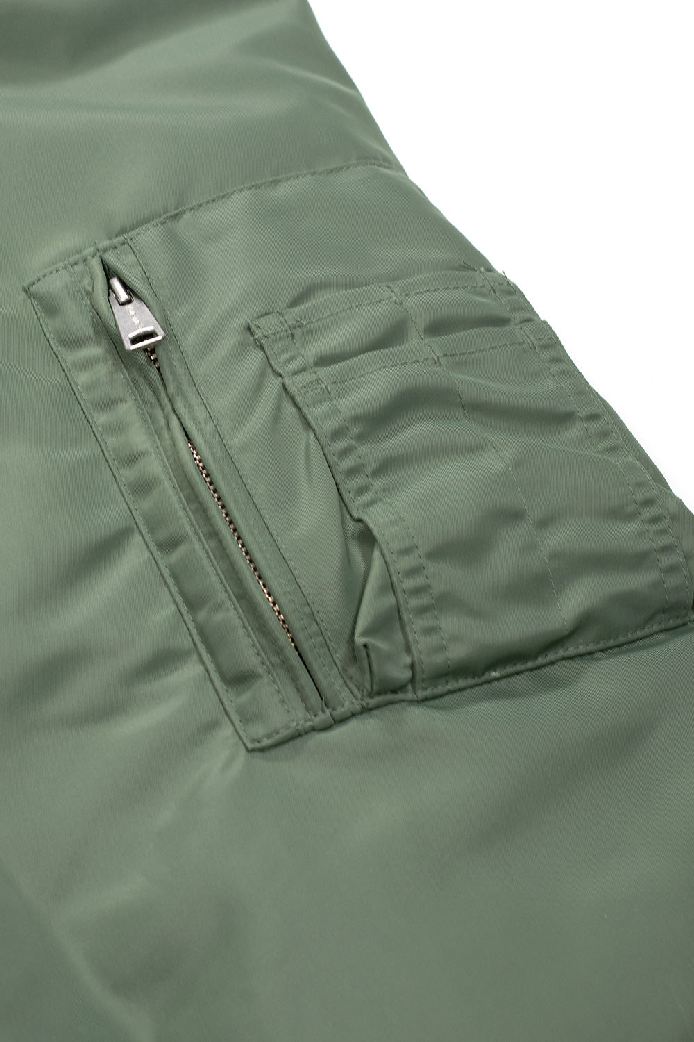 "Nahaufnahme der Carhartt WIP Olten Bomber Jacket in Duck Green/Turmeric – robuste Materialien und kontrastreiche Farbkombination für einen einzigartigen Look"
