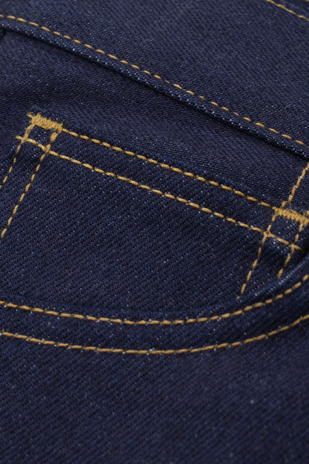 Extreme close-up detail of the front right coin pocket on the Carhartt WIP Payson Pant Blue Rigid, highlighting the reinforced bar-tack stitching, clean curved pocket edge, and crisp twill grain of the raw unwashed indigo denim fabric.