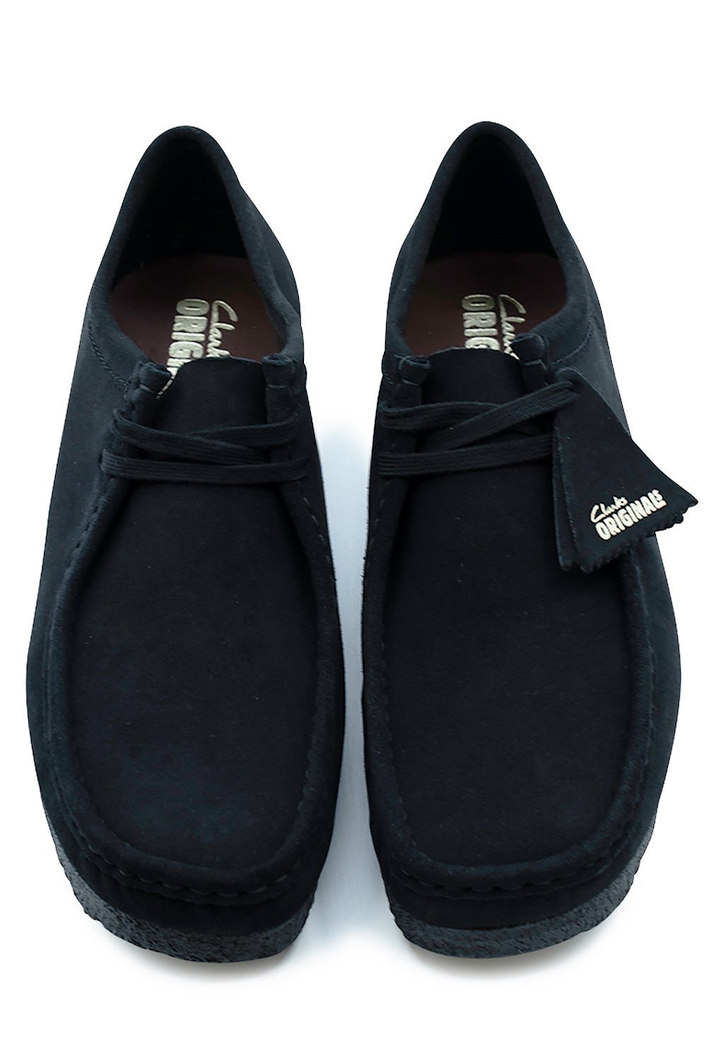 Top-down perspective of a pair of Clarks Originals Wallabee low-top shoes in Black Suede, showing the classic square apron toe box, black waxed cotton laces, clean structural seams, and dark leather insoles printed with gold Clarks Originals branding.
