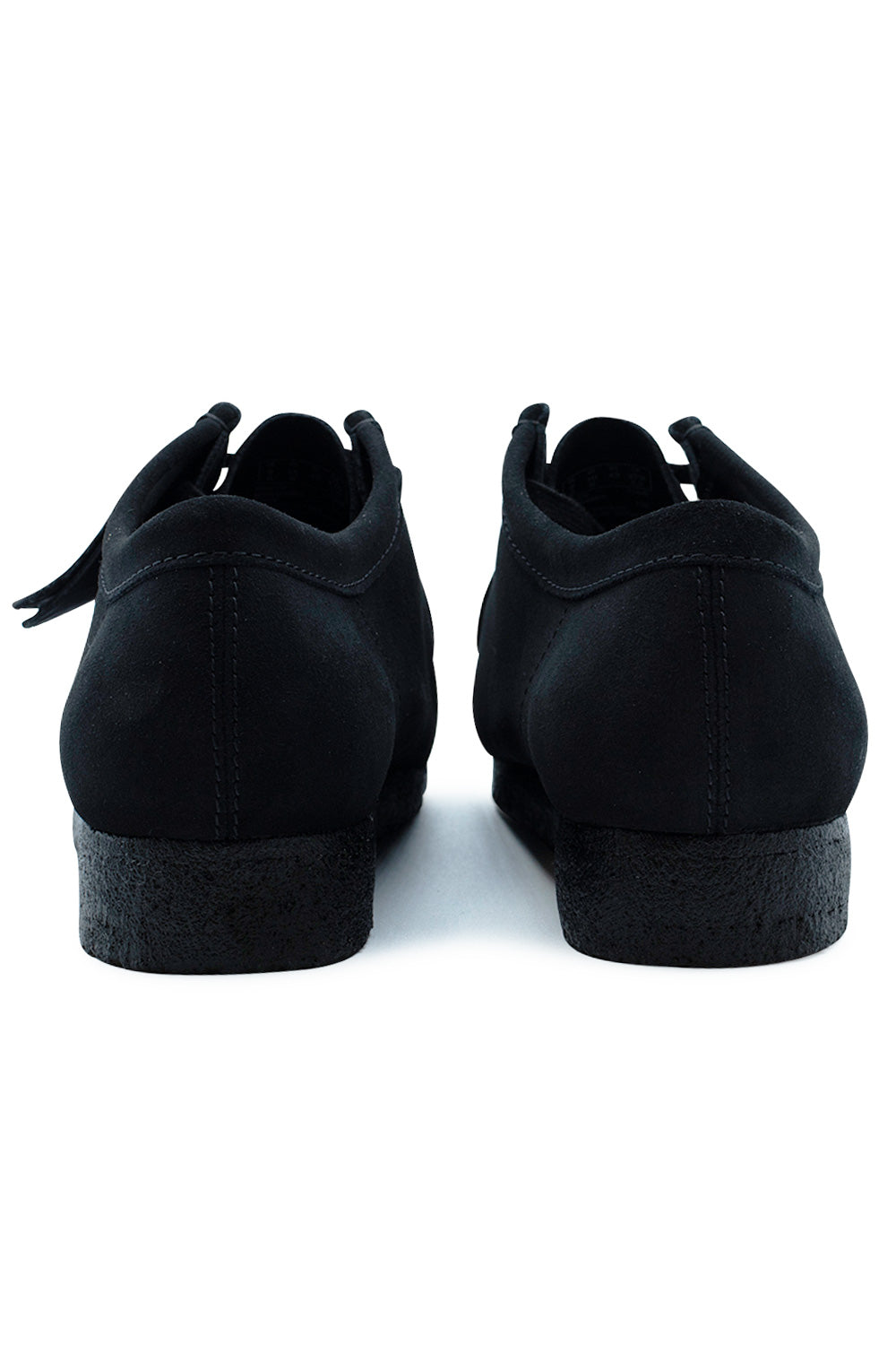 Rear view of the heels of the Clarks Originals Wallabee Black Suede shoes, highlighting the smooth black suede heel counter with vertical double contrast stitching and the thick black textured pebble crepe rubber heel.