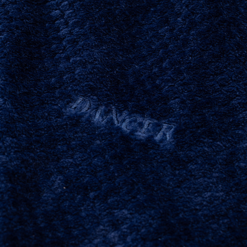Detailed macro shot of the left chest branding on the Dancer Fleece Half Zip, showcasing the neat tonal navy satin-stitch embroidery of the "DANCER" block letter logo sunk into the thick, plush navy fleece fabric.