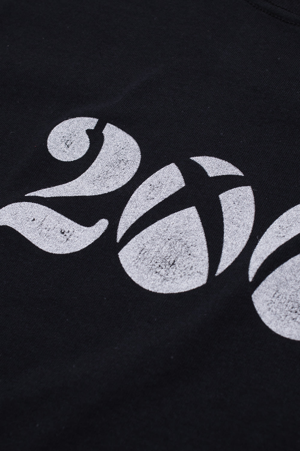 Detailed close-up view of the back graphic print on the black Fuck This Industry Est 2008 T-Shirt, showing the cracked distressed white ink detailing on the number 2 and the spherical segmented cross-logo replacing the number 0, referencing Y2K skate and gaming culture