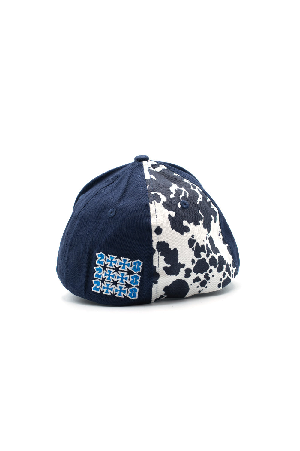 Rear three-quarter perspective of the Fuck This Industry Sorry Hat, showing the asymmetrical color-blocked design featuring a navy blue back panel embroidered with a 3x3 grid of blue and white "2008" cross graphics alongside a contrasting white panel covered in a dark navy printed cow pattern