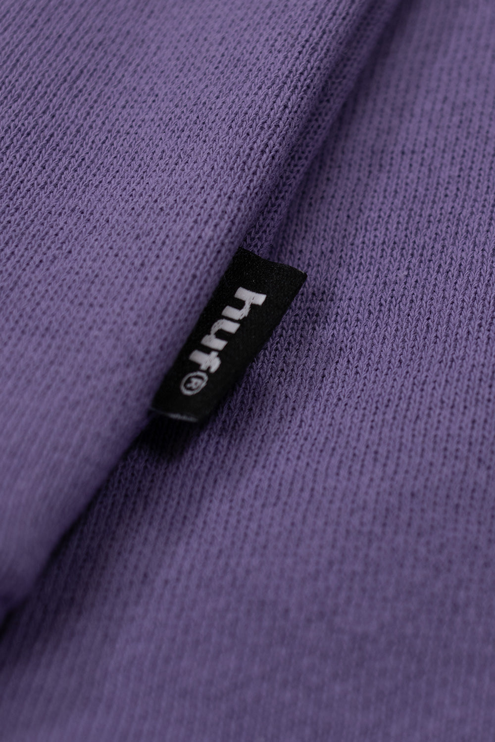 Close-up of the printed Huf 89 Outline logo on a soft-brushed Dust Purple fleece sweatshirt.