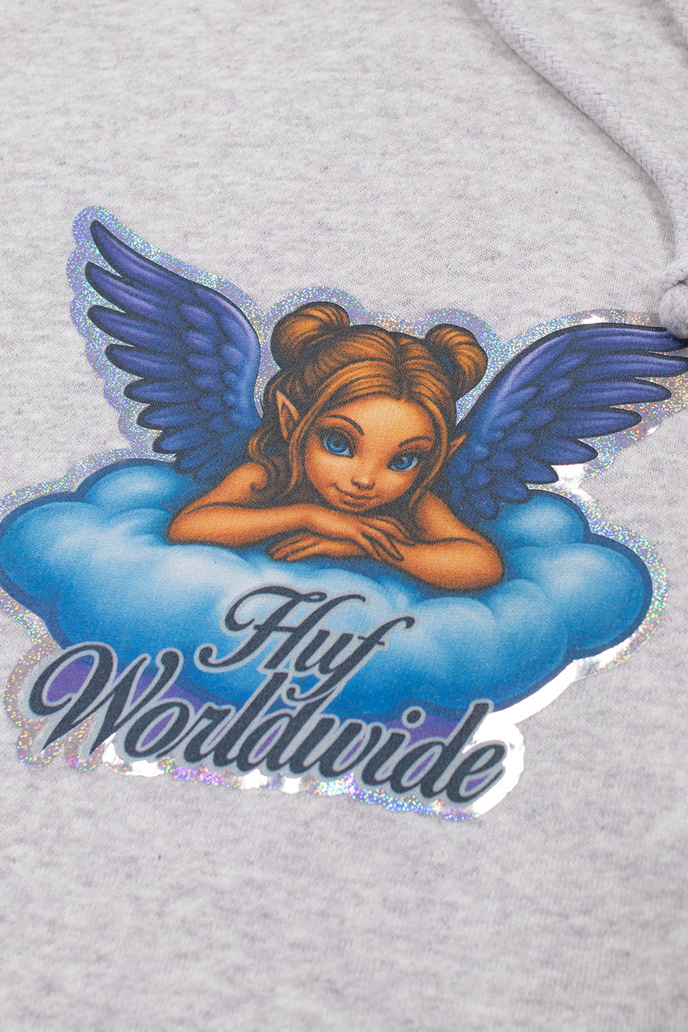 Detailed close-up view of the front chest graphic on the heather grey HUF Bliss Hoodie, showcasing the illustrated winged cherub fairy resting on a soft blue cloud, cursive dark blue "Huf Worldwide" typography, and the sparkling holographic glitter foil border framing the artwork against the textured grey fleece