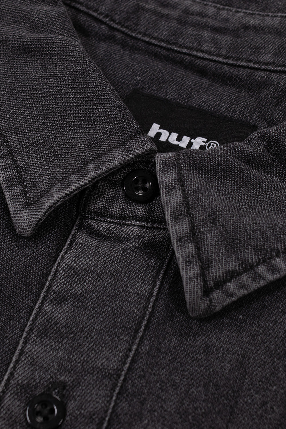 Detailed close-up shot of the collar and upper front placket on the washed black HUF Carson Denim Shirt, highlighting the point collar stitching, tonal black engraved buttons, interior black woven "HUF" neck label, and the textured acid-washed twill pattern