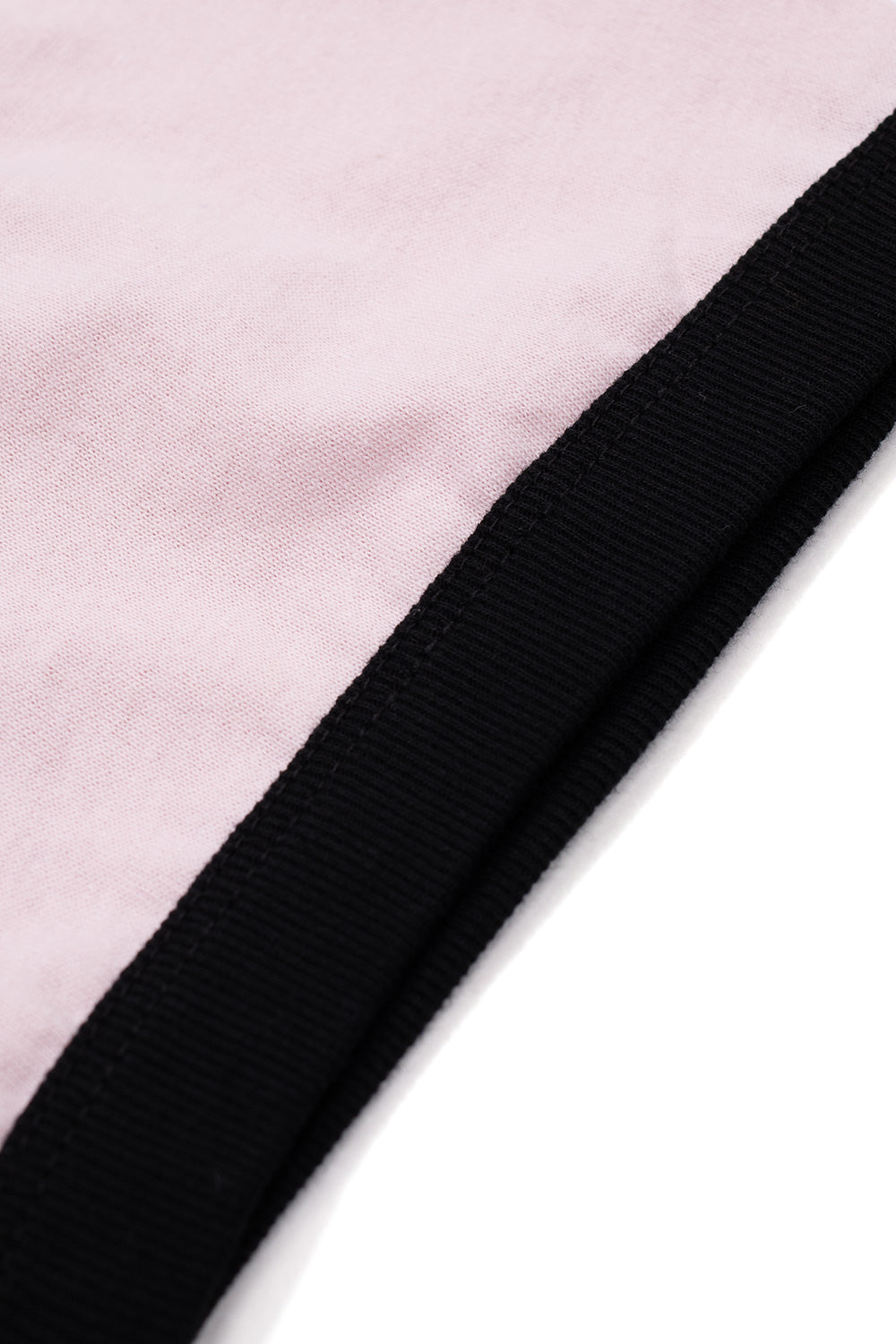 Macro studio close-up of the sleeve construction on the HUF Cherries Ringer T-Shirt, displaying the contrast between the soft dusty pink cotton jersey fabric and the tightly ribbed black elastic cuff with fine tonal topstitching.