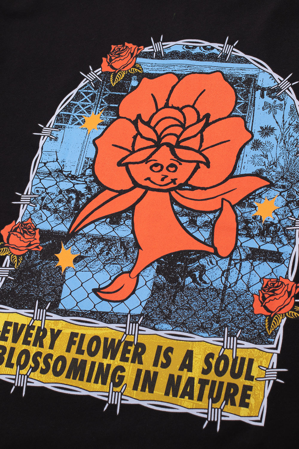 Detailed close-up shot of the large back graphic on the black HUF Flower District T-Shirt, displaying the screen-printed red-orange flower character, barbed wire borders, blooming red roses, and the distressed yellow slogan sign across the black cotton fabric