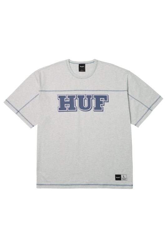Front view of the heather grey HUF Legacy Football T-Shirt, crafted from heavy 240g 100% cotton jersey in an oversized boxy silhouette, showcasing a large navy blue collegiate HUF chest print with white outlines, dark blue contrast flatlock stitching along the horizontal yoke and sleeves, and a woven locker patch on the lower left hem.