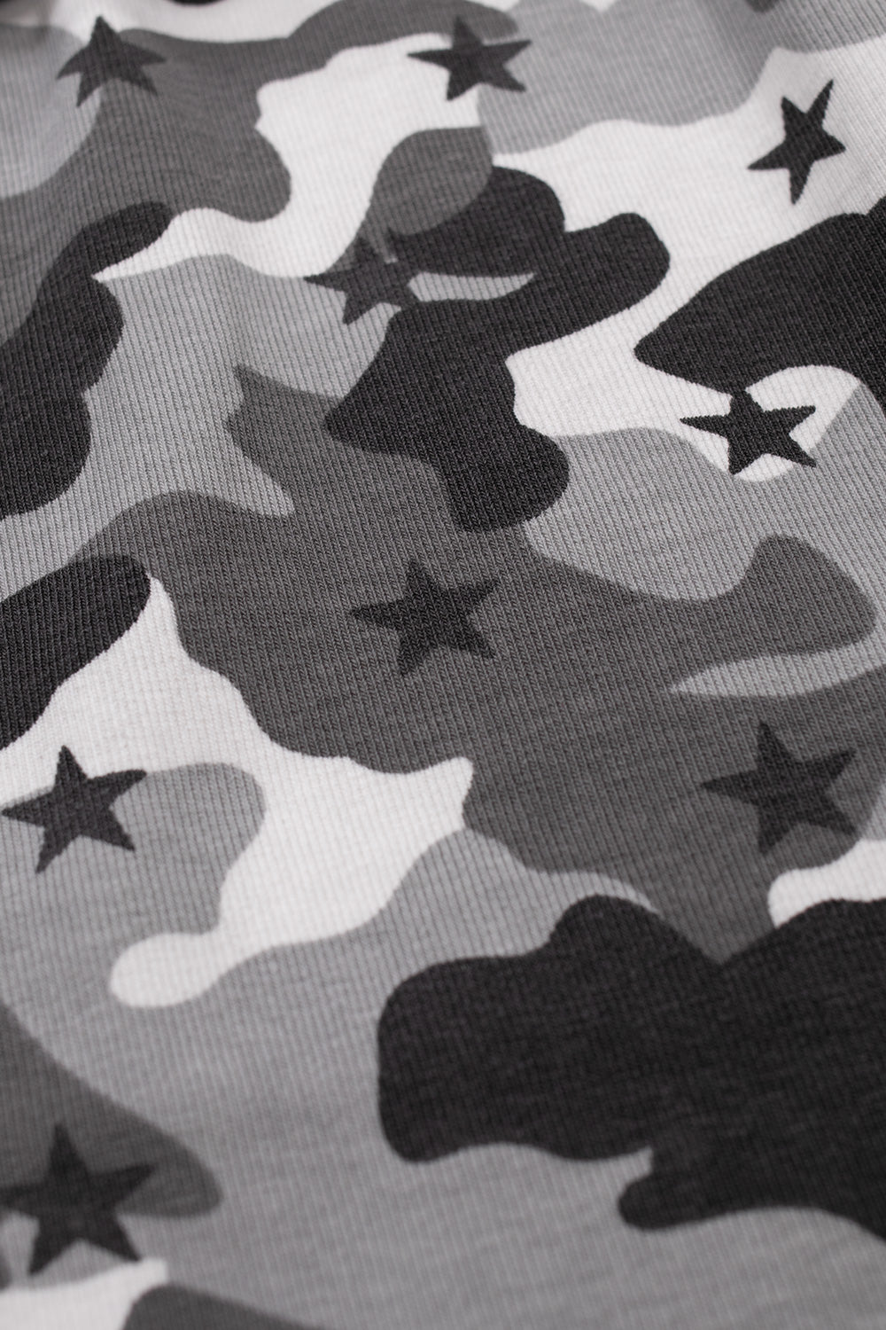 Macro texture detail of the sewn-in sleeve fabric on the HUF Shadows Work Shirt, displaying the soft cotton-spandex stretch jersey printed with a multi-tonal grey, black, and white camouflage pattern accented by scattered black five-point stars