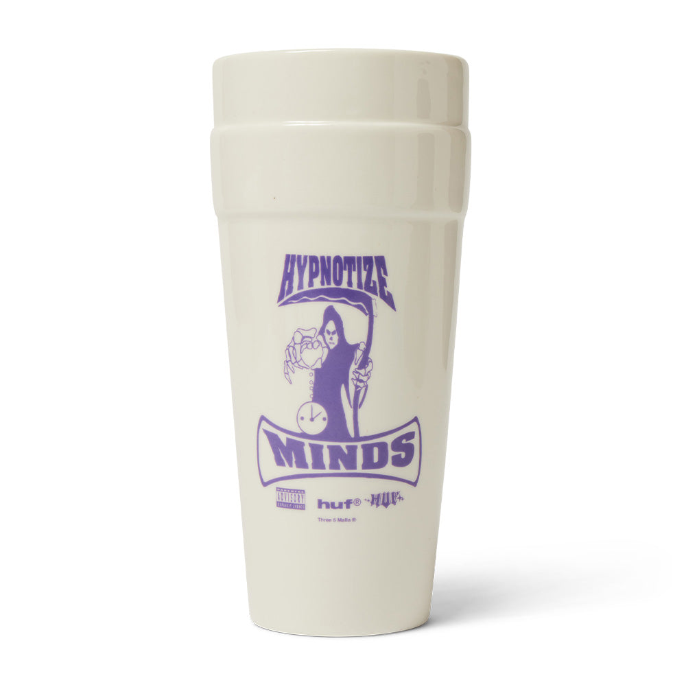 Front studio view of the white Huf X Three 6 Mafia Ceramic Double Cup, molded from glazed white ceramic in the shape of two stacked styrofoam cups, decorated with a bold purple printed Hypnotize Minds record label graphic featuring the grim reaper, an hourglass clock, Parental Advisory badge, and the HUF logo.