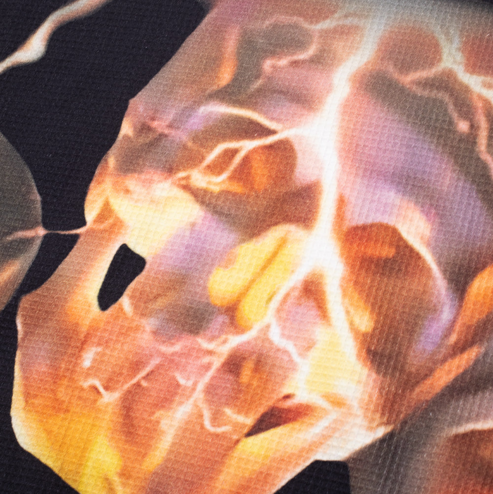 Extreme close-up macro texture shot of the flaming skull graphic on the Huf X Three 6 Mafia Torched Longsleeve Thermal, showing the vivid orange and yellow fiery glow, electric lightning crackles, and the defined honeycomb waffle knit structure.