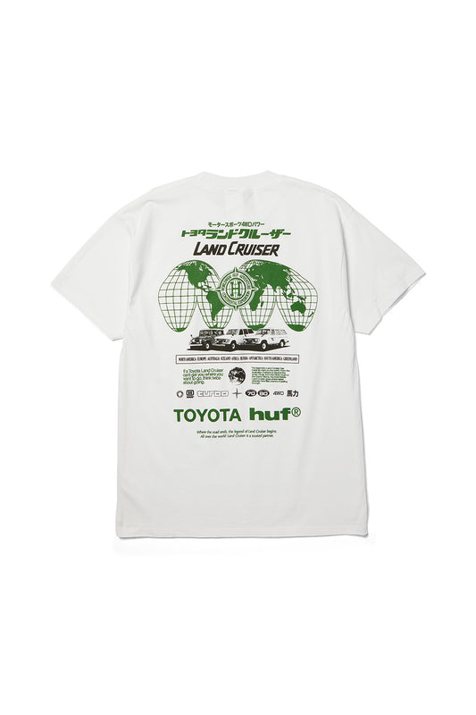 Back flat lay view of the white Huf X Toyota Land Cruiser Global SS T-Shirt in 200g cotton, showcasing an oversized retro 4x4 expedition back print featuring green wireframe globe hemispheres, Japanese katakana typography, three generations of vintage Toyota Land Cruisers, a continental travel checklist, technical badges, and bold green "TOYOTA huf®" branding.
