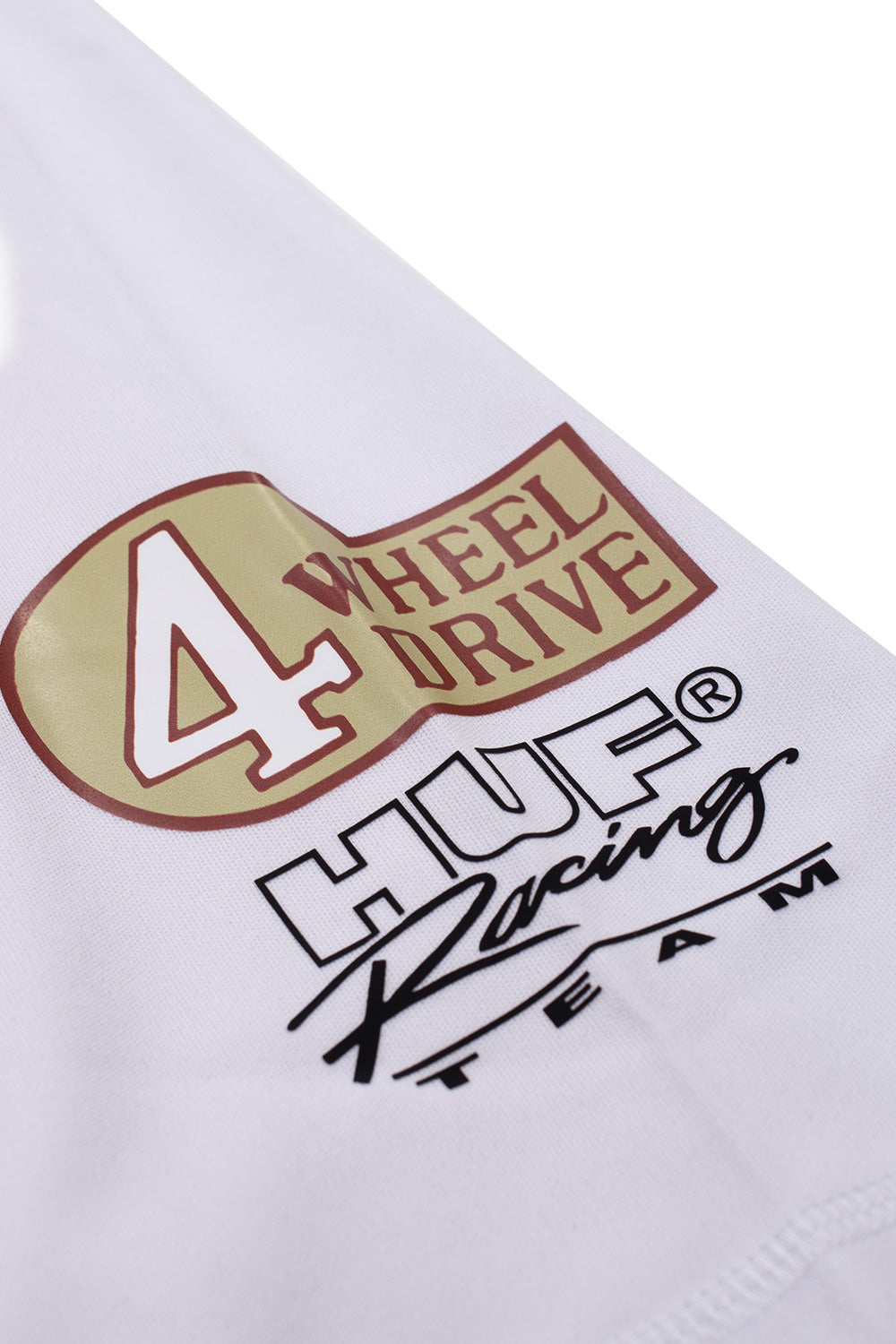 Studio close-up view of the right sleeve graphic on the Huf X Toyota Land Cruiser Rally Jersey, showcasing a vintage motorsport-inspired gold-and-red badge reading "4 WHEEL DRIVE" positioned directly above a black screen-printed "HUF Racing TEAM" logo.