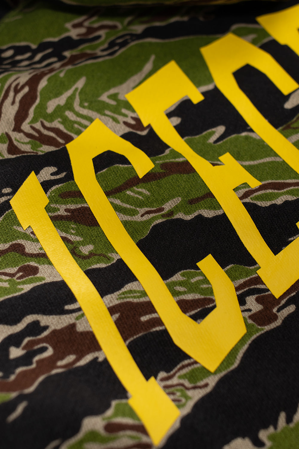 Yellow printed ICECREAM lettering on the back of the Smiley Tiger Stripe camo hoodie, premium graphic streetwear with bold skate aesthetics.