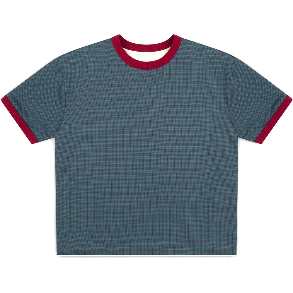 Front flat lay studio view of the reversed side of the Metalwood Studio Dual Face T-Shirt, displaying the all-over muted slate blue and grey micro-grid check pattern, contrast burgundy ribbing at the neck and cuffs, and subtle exposed bone-white fabric along the inner collar and lower hem edge.